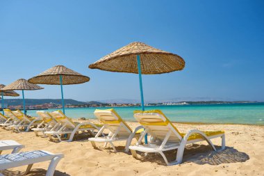 Açık deniz kıyısındaki Ilica plajında boş güneşlikler, Cesme, Türkiye