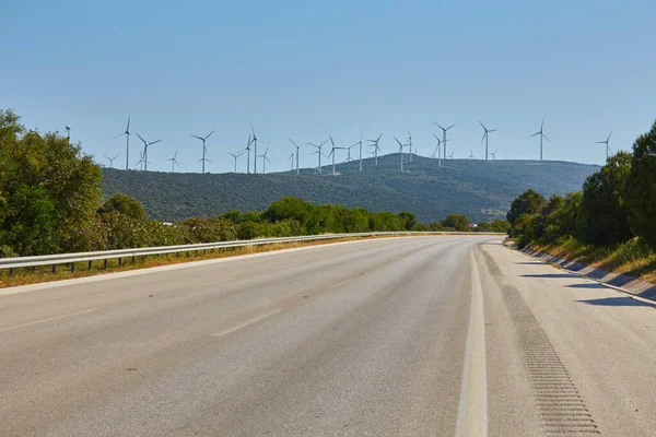 Uzakta Rüzgar Türbinleri Olan Tepelerden Geçen Bir Yol — Stok fotoğraf