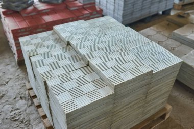 Paving levha fabrikası. Paletlerin içinde fayanslar yığılmış. Fabrikada üretim için kaldırım döşemeleri var.