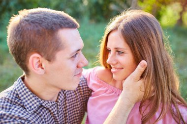 Açık havada aşık olan genç bir çift. Yazın tarlada poz veren genç şık moda çiftlerinin çarpıcı şehvetli portresi. Güneşli renkler..