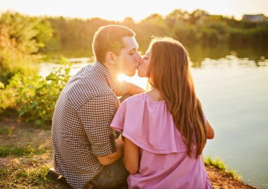 Nehrin Tadını Çıkarıyorum. Nehirde gün batımında flört eden romantik, gülen bir çift..