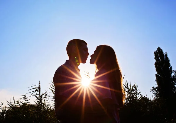 若いカップルのシルエットキスでビーチで彼らの後ろに太陽が沈む — ストック写真