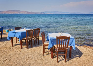 Geleneksel mavi masa ve sandalyeli Yunan plajı, Yunanistan.