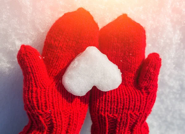 Kalp şeklinde kar taneleri kırmızı eldivenler üzerinde