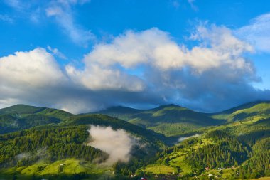 Dağlardaki yaz manzarası ve bulutlu koyu mavi gökyüzü.