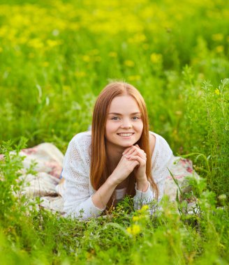 Güneşli bir günde kolza tohumu tarlasında kızıl saçlı kız.
