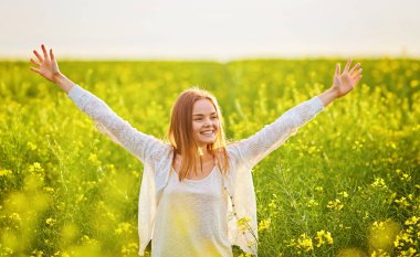 Yeşil mısır gevreği tarlasında açık kollu kızıl saçlı kız..