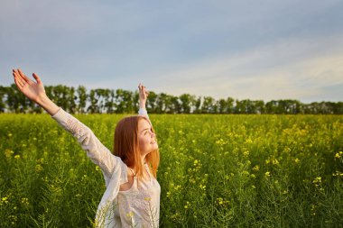 Yeşil mısır gevreği tarlasında açık kollu kızıl saçlı kız..