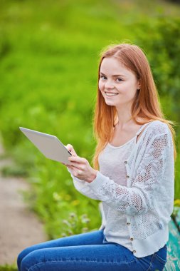 Dışarıdaki çimlerin üzerine kalem yazan kızıl saçlı kız.