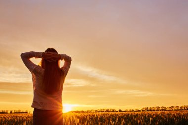 Gün batımında mutlu genç bir kadının silueti, tarlada açık bir kız.