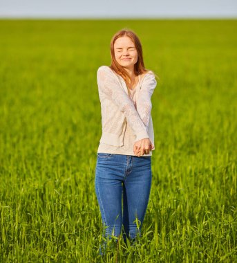 Çimlerin üzerinde güzel piknik. Yeşil tarlanın ortasında güzel, kızıl saçlı bir kadın iyi vakit geçiriyor. Yaz manzarası, güzel hava. Güneşli ve bulutlu rüzgarlı bir gün.