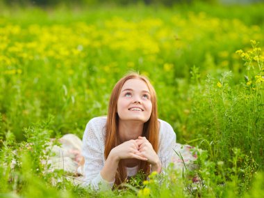 Güneşli bir günde kolza tohumu tarlasında kızıl saçlı kız.