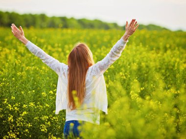 Yeşil mısır gevreği tarlasında açık kollu kızıl saçlı kız..