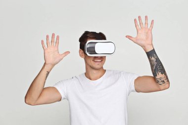 Beyaz izole edilmiş arka planda sanal gerçeklik gözlüklü adam. VR kulaklıklı genç adam interaktif ekrana bakıyor..