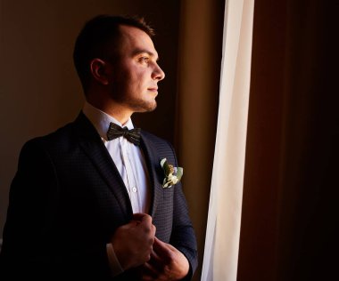 Pahalı bir iç mekanda düğün sabahı damadı. Düğününde mutlu damat. Damat evde giyinmiş. Moda. Düğünden önce damat hazırlığı.