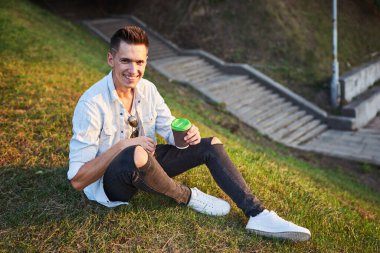 Hippi adam elinde hazır kahveyle, mutlu bir şekilde gülümsüyor ve caddede yürüyor. Gözlüklü, kaygısız yakışıklı adam. Milenyum nesli