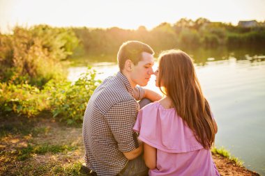 Nehrin Tadını Çıkarıyorum. Nehirde gün batımında flört eden romantik, gülen bir çift..