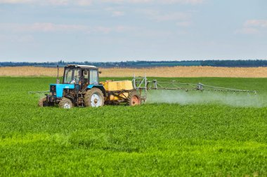 Small Tractor spraying pesticides at wheat fields clipart