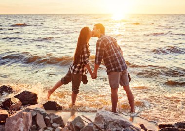 Gün batımında sahilde yürüyen bir çift.