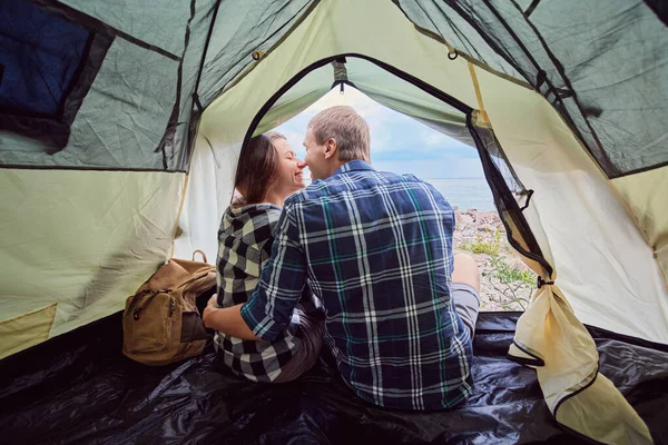 Romantic couple camping outdoors and sitting in a tent. Happy Man and woman on a romantic camping vacation.