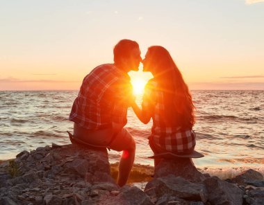 Adam ve kadın doğa gezintisindeler. Aşk ve aşk. Günbatımında öpüşmek.