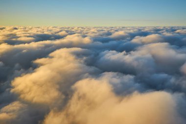 Uçak penceresinden bulutların üzerinde gün batımının muhteşem görüntüsü