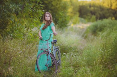 güzel genç kadın alanında eski bir bisiklet ile