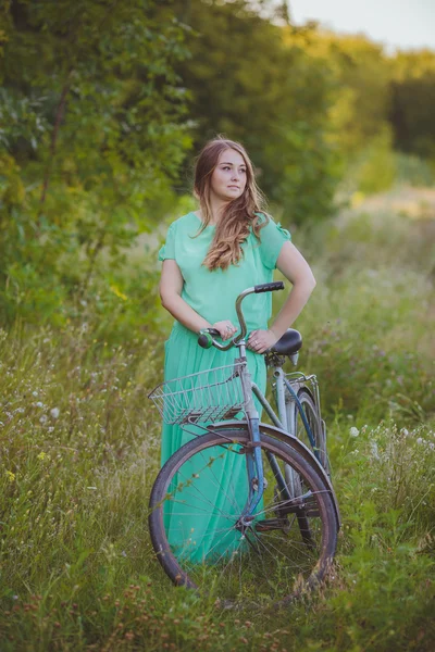 Belle jeune femme avec un vieux vélo dans le domaine — Photo