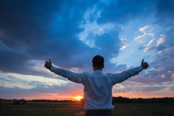 Empresario de pie en el campo para hacer frente a la puesta de sol — Foto de Stock