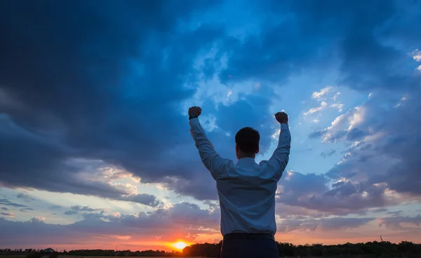 Businessman standing on field to face the sunset — Stock Photo, Image