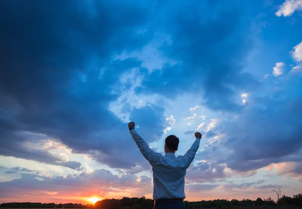 Businessman standing on field to face the sunset — Stock Photo, Image