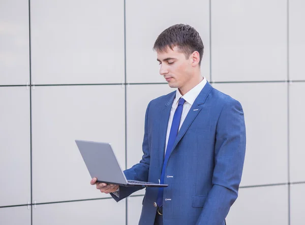 Succesvolle zakenman permanent in de straat met een laptop — Stockfoto