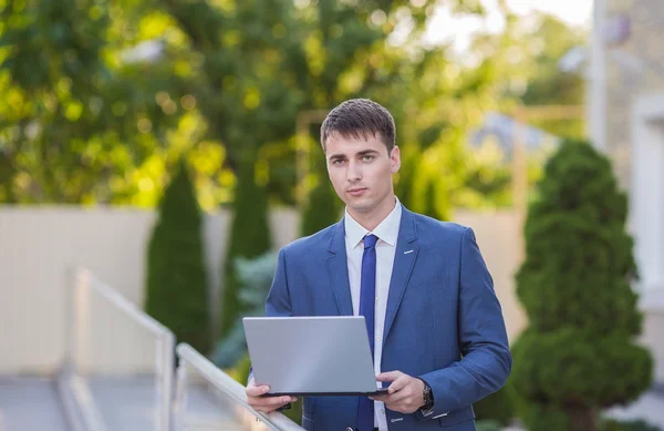 Succesvolle zakenman permanent in de straat met een laptop — Stockfoto