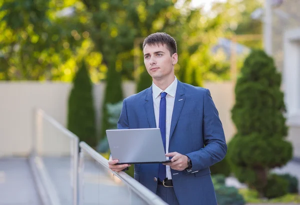 Успешный бизнесмен, стоящий на улице с ноутбуком — стоковое фото