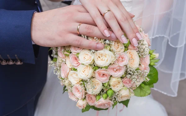 Hands and rings on wedding bouquet — Stock Photo, Image