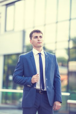 Bulanık arka plan üzerinde duran genç bir işadamı portresi