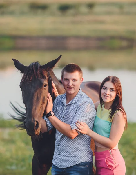 Young couple spending time together with their horse — Stock Photo, Image