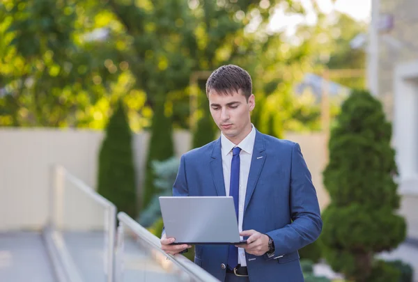 Succesvolle zakenman permanent in de straat met een laptop — Stockfoto