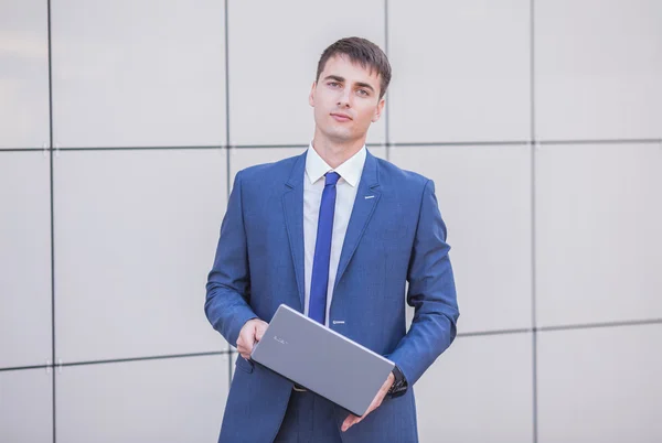 Succesvolle zakenman permanent in de straat met een laptop — Stockfoto