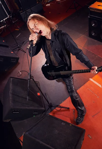 Guitarrista de cabelos compridos está tocando e cantando — Fotografia de Stock