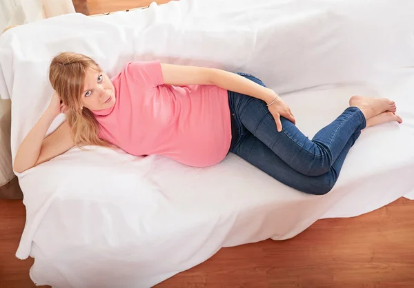 Mujer embarazada relajándose en casa en el sofá — Foto de Stock