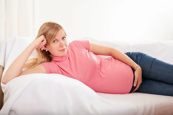 妊娠中の女性が自宅でソファでリラックス — ストック写真