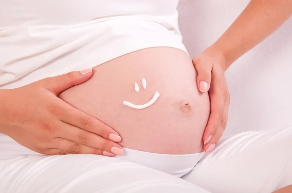 Vientre de la mujer embarazada con el símbolo de la sonrisa en él — Foto de Stock