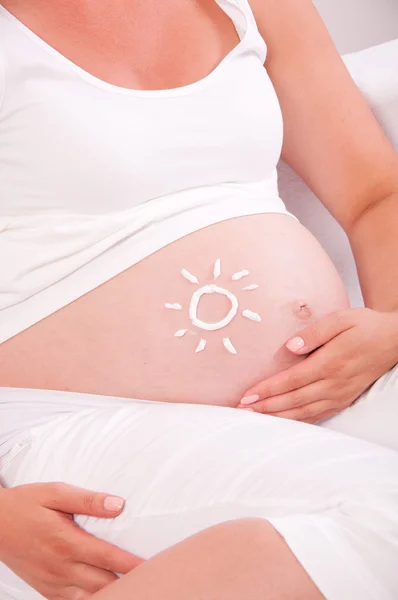 Barriga de mulher grávida com símbolo de sol nele — Fotografia de Stock