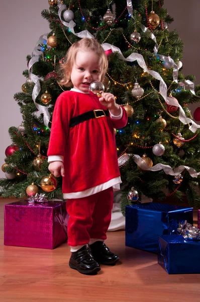 Roztomilá holčička v kostýmu Santa u vánočního stromu — Stock fotografie