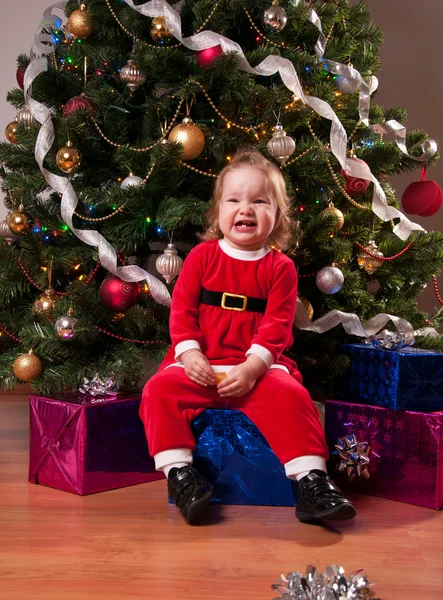 Niedliches kleines Mädchen im Weihnachtsmannkostüm in der Nähe des Weihnachtsbaums — Stockfoto