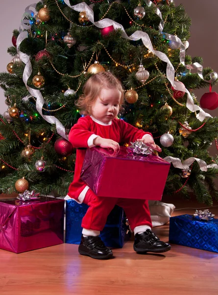 近くクリスマス プレゼントを開くサンタ衣装でかわいい赤ちゃん女の子 — ストック写真