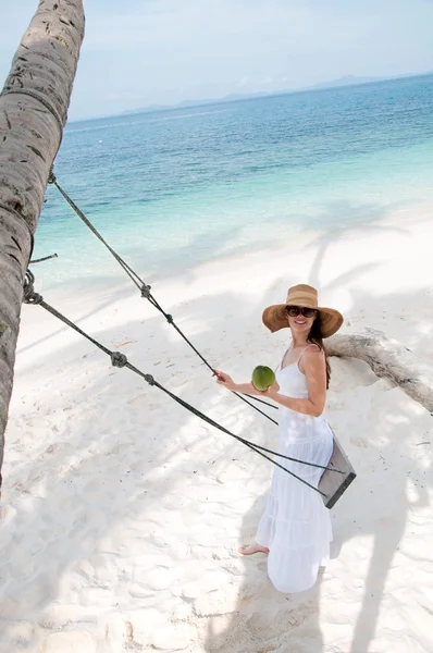 Vrouw in witte jurk swingende op tropisch strand — Stockfoto