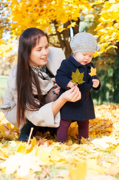 Jonge gelukkig moeder met dochter in herfst park — Stockfoto