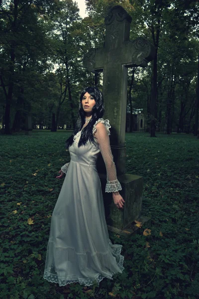 Witch from the cemetery, in front of cross — Stock Photo, Image